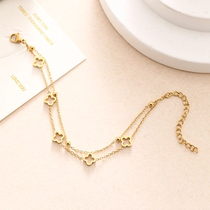 Detailed close-up of golden double-layer chain bracelet with hollow clover charms