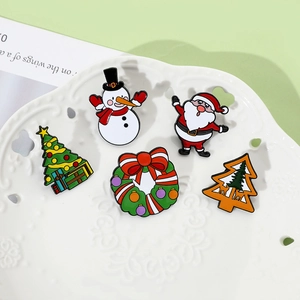 Close-up of five colorful Christmas enamel pins featuring Santa and snowman on a ceramic tray