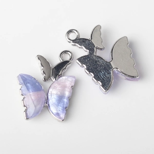 Detailed macro view of purple and pink pearlescent butterfly pendant with metal back