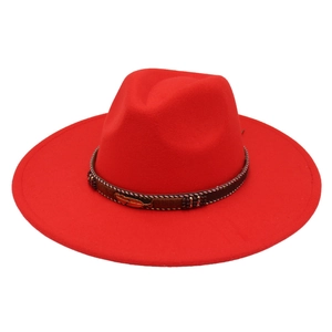 Detail of red wool felt fedora featuring a brown band with a golden feather ornament