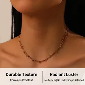 Détail d'un collier à double chaîne dorée avec billes sur un mannequin au style minimaliste