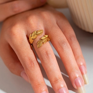 Detailed shot of golden feather open ring showing intricate leaf texture on fingers