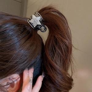 Detail of star-shaped rhinestone claw clip securing a high ponytail in brown hair