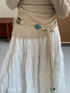 Close-up of bohemian woven belt with turquoise oval charms and long tassels