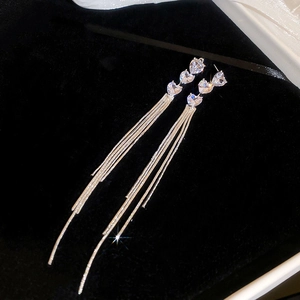 Close-up of silver bow heart earrings with sparkling crystals on black velvet background