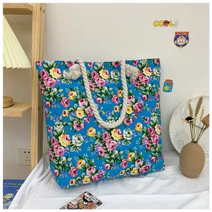 Detailed close-up of large blue floral tote bag with pink roses and thick rope handles