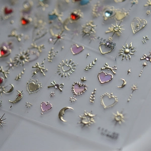 Detail of 3D nail art stickers with gold stars and colored crystal heart designs