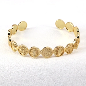 Close-up of vintage gold brass religious Saint Benedict medallion embossed open bangle