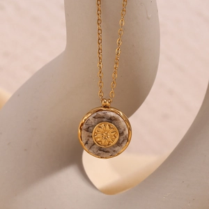 Detail of 18K gold-plated sunburst pendant with natural grey marble stone texture