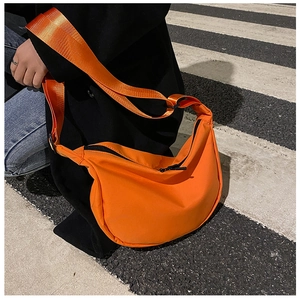 Close-up of bright orange crescent nylon bag with wide adjustable shoulder strap