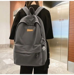 Rear view of a grey nylon backpack with astronaut charm and Coolboy patch