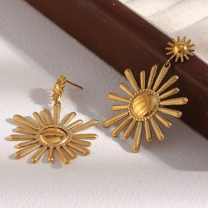 Detail of 18K gold plated stainless steel sunflower earrings on fabric near jewelry box
