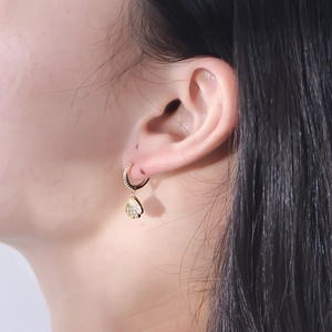 Close-up of elegant gold shell drop earrings with pavé crystals on a female model