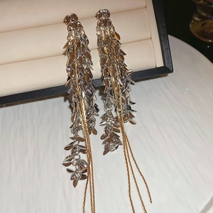 Gros plan sur les boucles d'oreilles à pompons en épi de blé argenté et chaînes dorées
