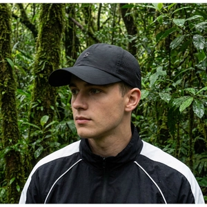 Detail of black breathable baseball cap with laser-cut S logo and curved brim for men