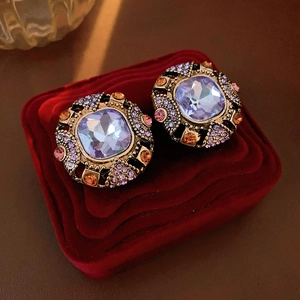 Detailed close-up of vintage gold earrings with purple stones on red velvet background