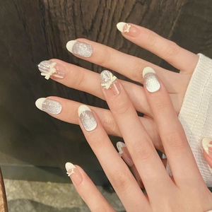 French ballerina style almond press-on nails with silver glitter and 3D white bow accents