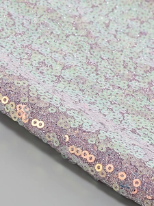 Macro shot of iridescent sequins and gold accents on a luxury cocktail dress fabric