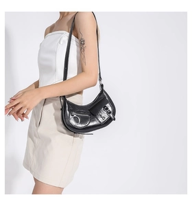 Détail du sac croissant noir de style motard avec anneaux métalliques et cuir PU brillant