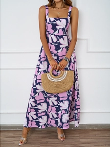 Detail of floral summer maxi dress with spaghetti straps and a woven straw bag