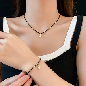 Detail of bohemian necklace and bracelet set with black beads and gold shell charms