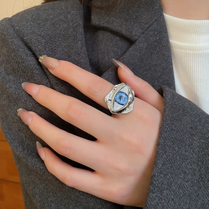 Detailansicht eines silbernen Evil Eye Rings mit blauem Auge am Finger getragen