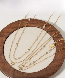Detail of layered stainless steel gold necklaces with natural pearls and star charms
