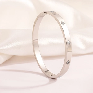 Elegant silver four-leaf clover bangle with zircon inlays on a silk background
