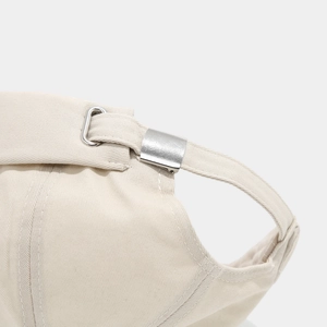 Detailed close-up of the adjustable silver metal D-ring buckle on a beige cotton brimless cap