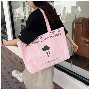 Detail of pink canvas tote bag with black floral art print and studio lettering
