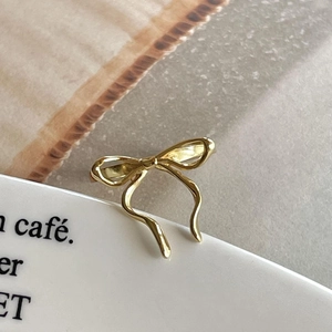 Macro view of a gold-toned bow-shaped 925 sterling silver ring with metallic finish
