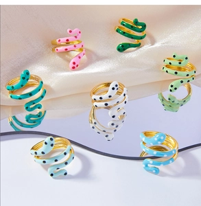 Close-up of gold-plated snake rings with colorful enamel and dot patterns on mirrors