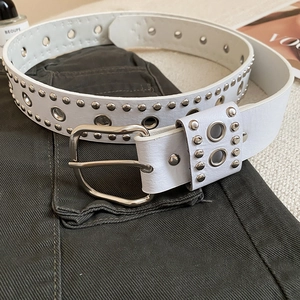 Vue détaillée de la ceinture en cuir blanc avec rivets argentés et boucle carrée en métal