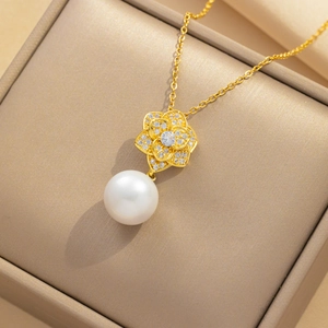 Golden camellia flower pendant necklace with white pearl drop in a jewelry box