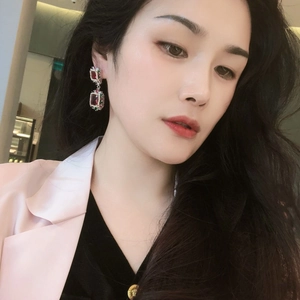 Detail of luxury colorful zircon flower earrings with pink and green gems on model