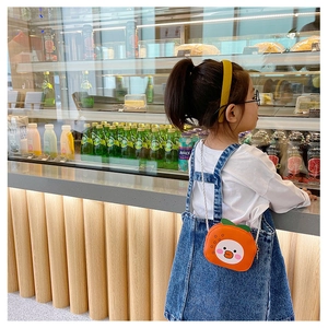 Close-up of cute orange fruit-shaped crossbody bag for girls with a cartoon duck detail