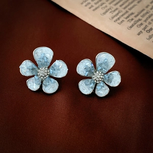 Detailansicht eisblauer Kristallblumen-Ohrstecker mit Silberrand auf rotem Samt