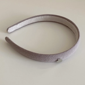 Détail du serre-tête en tricot gris-violet orné d'un petit pendentif en forme de cœur argenté