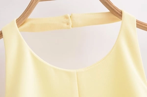Detail of light yellow halter neckline with double button closure on textured fabric