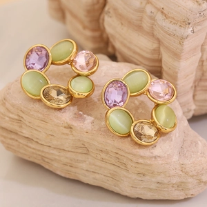 Gros plan de boucles d'oreilles fleuries dorées avec opales multicolores et cristaux sur pierre