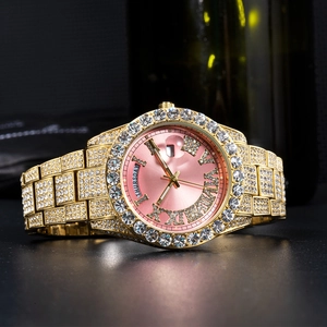 Detail of gold iced-out watch with pink sunray dial showing day and date display