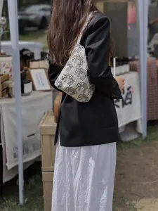 Detail view of ethnic elephant embroidery on cream canvas underarm bag for casual styling