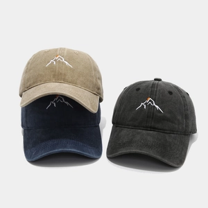 Close-up of embroidered mountain and sunset patterns on washed cotton baseball caps