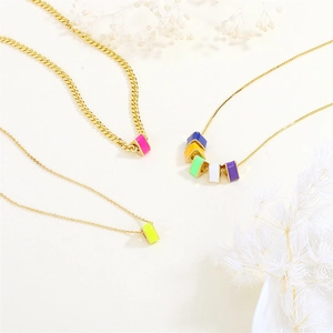 Close-up of colorful enamel cube charms on gold-plated chains with dried flowers
