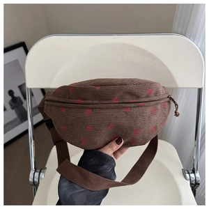 Detailed texture of brown corduroy bag with embroidered strawberry and zipper closure