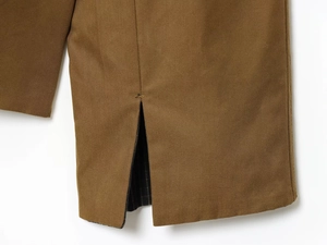 Close-up of side slit detail and twill fabric texture on a khaki short trench coat