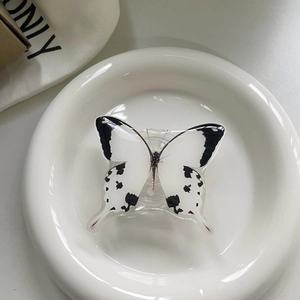 Close-up of a stylish black and white butterfly retractable phone grip on ceramic plate