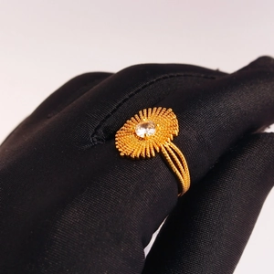 Vintage gold plated ring with radial texture and zircon stone on black gloved hand