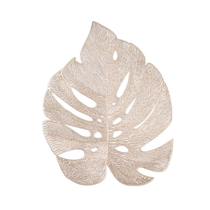 Rose gold Monstera leaf hollow PVC placemat with metallic finish on white background