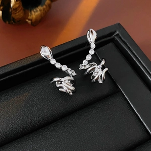 Detailed view of silver snake stud earrings with zircons on a black leather stand